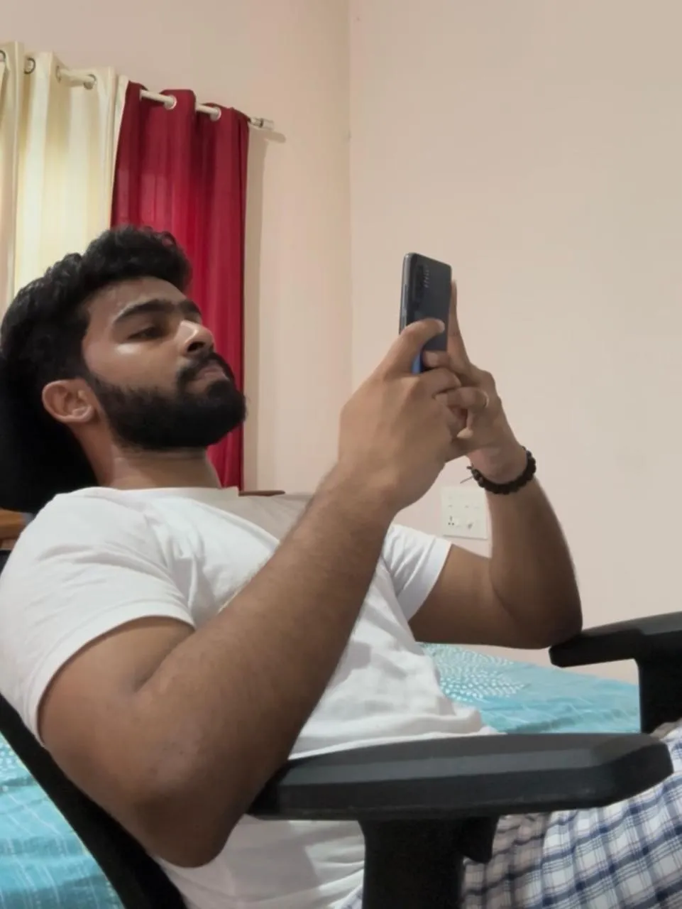 Akhil relaxing in a chair and watching reels on his phone